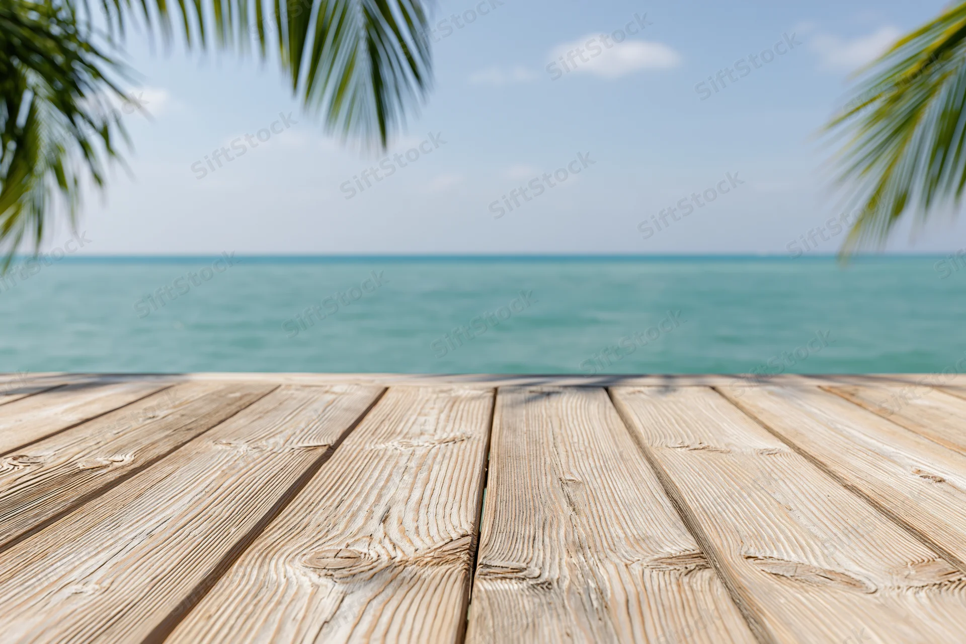 Wooden deck overlooking ocean with palm fronds framing the view