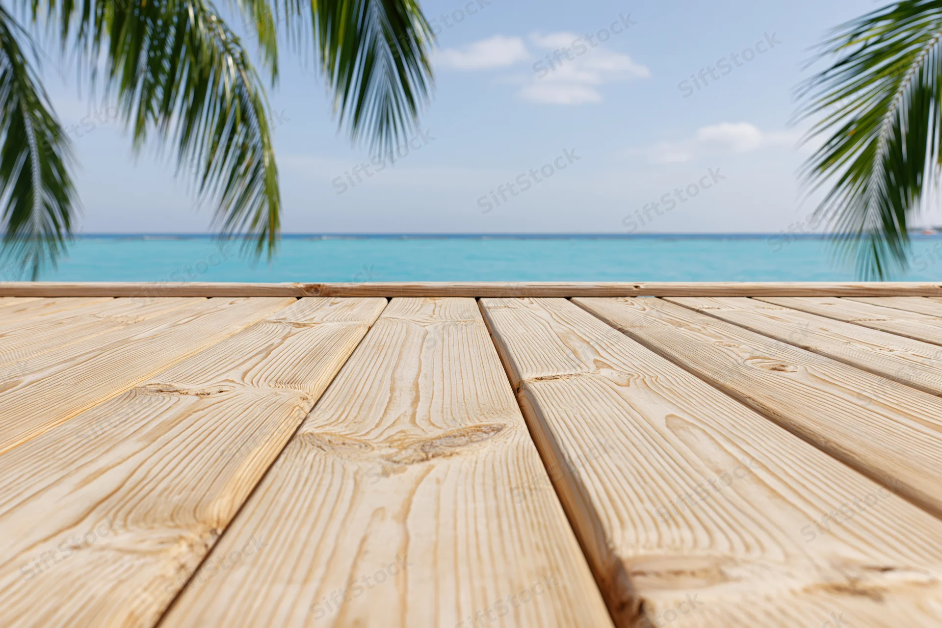 Wooden deck overlooking turquoise ocean with palm fronds framing the view