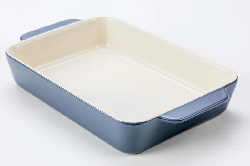 Blue ceramic baking dish with cream interior on white background
