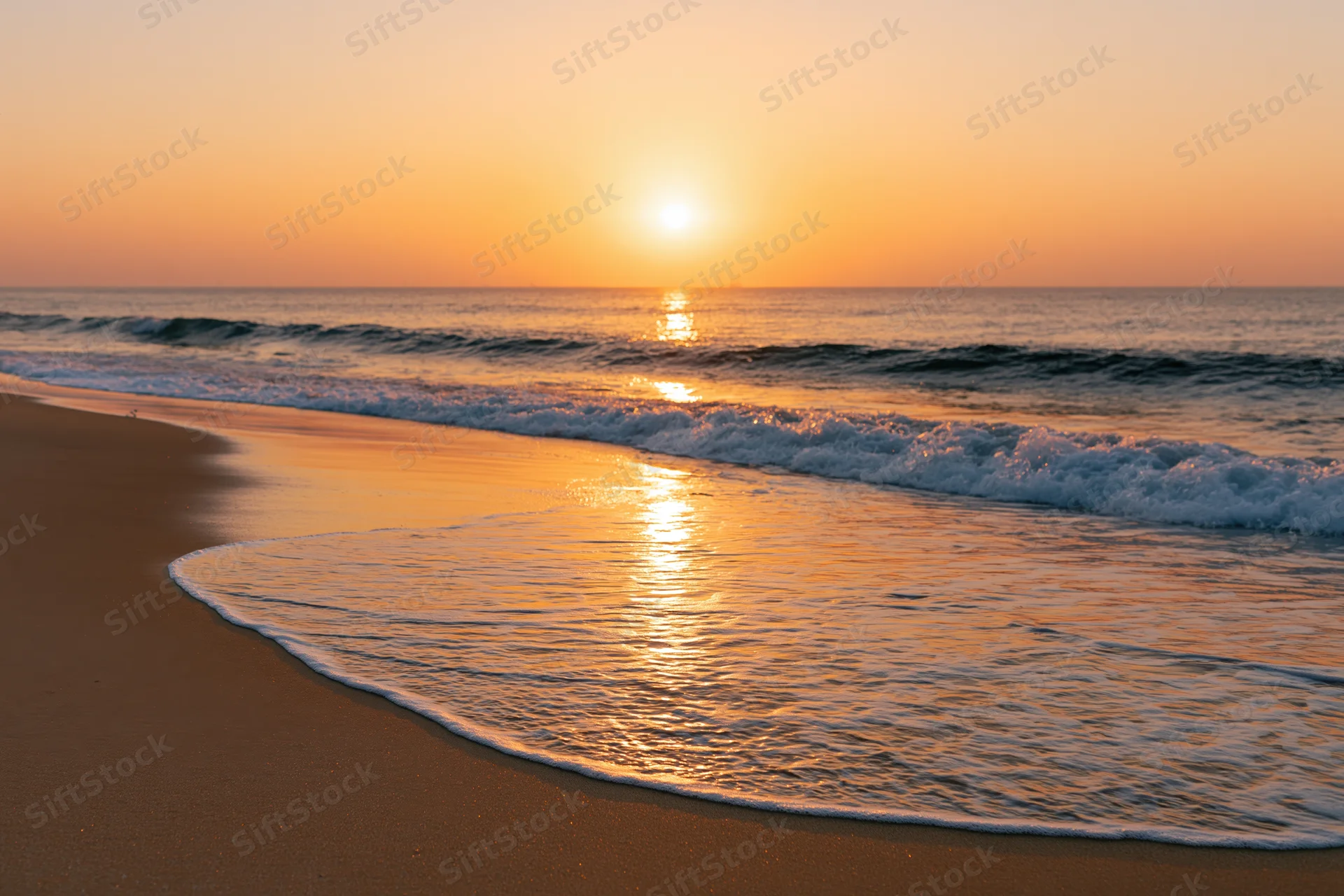 Sunset over ocean waves washing onto sandy beach at twilight