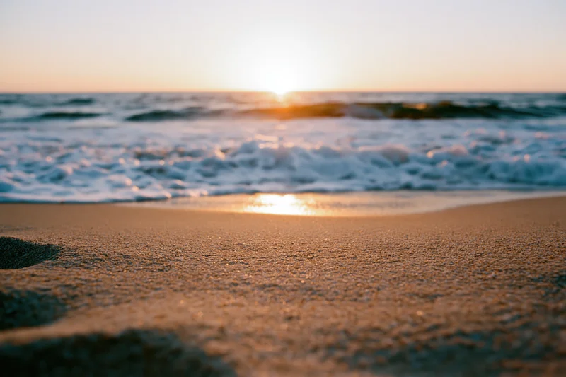 Sunset over ocean waves washing onto sandy beach at golden hour