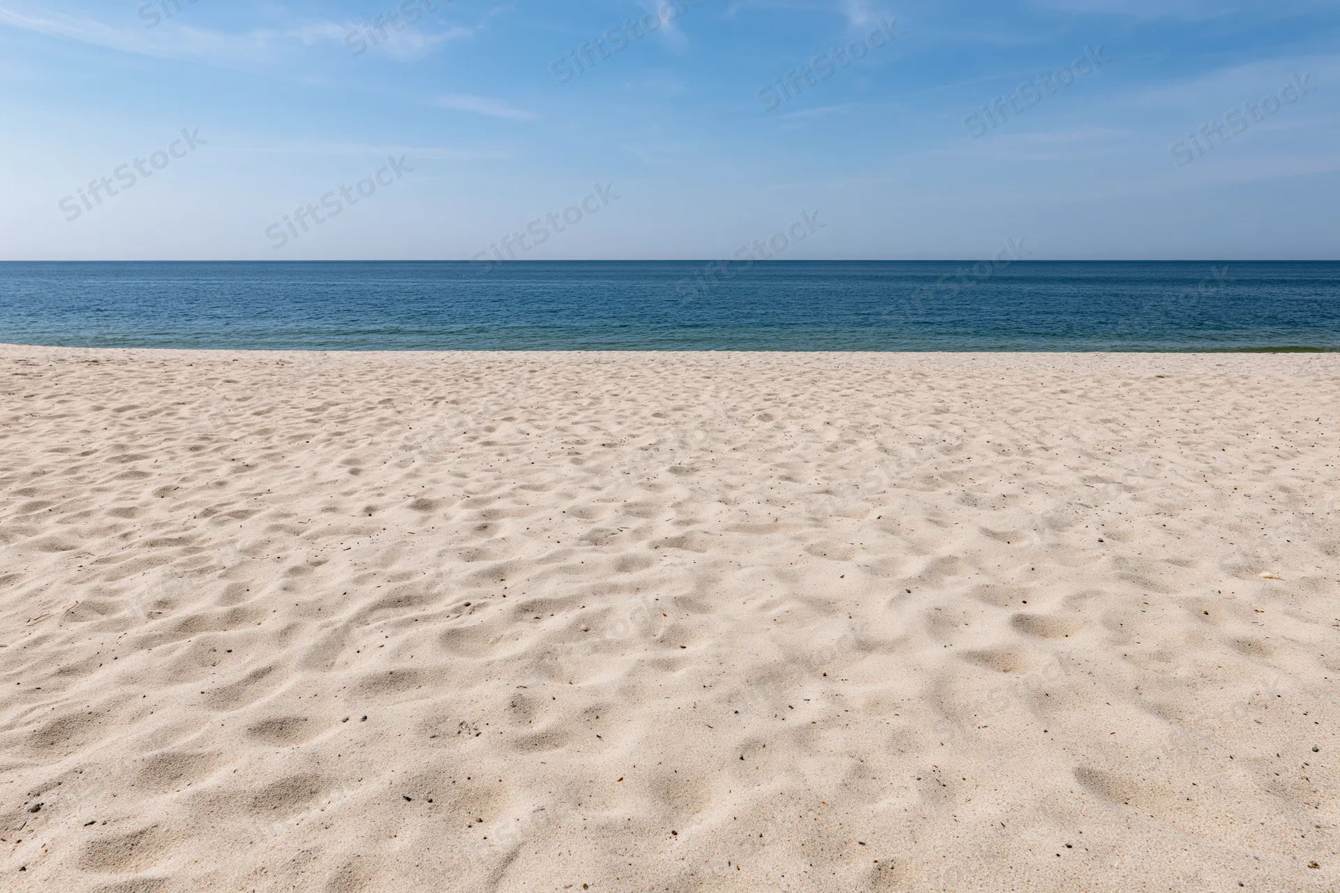 Sandy beach stretching to the ocean under a clear blue sky