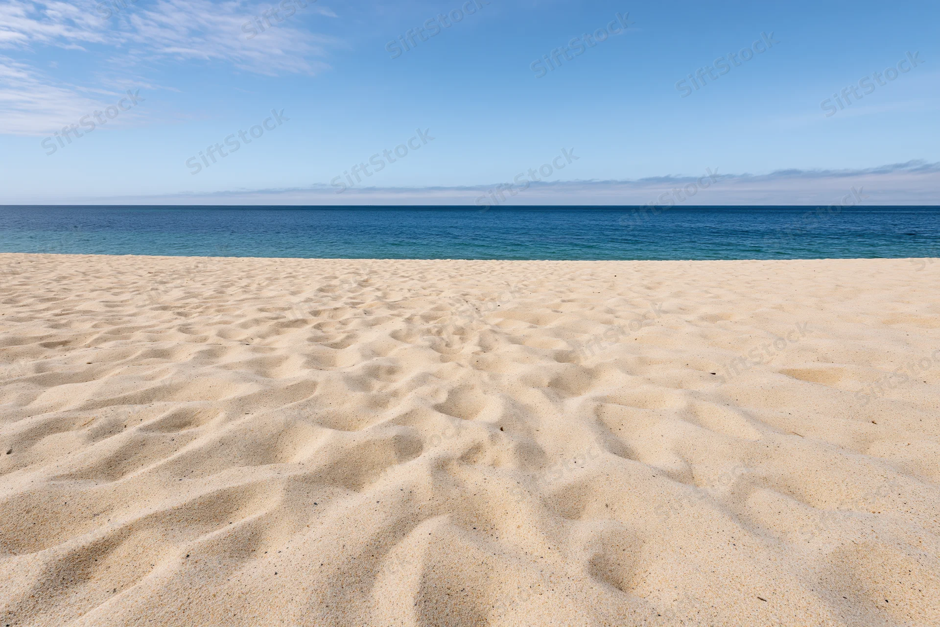 Sandy beach stretching to the ocean under a clear blue sky