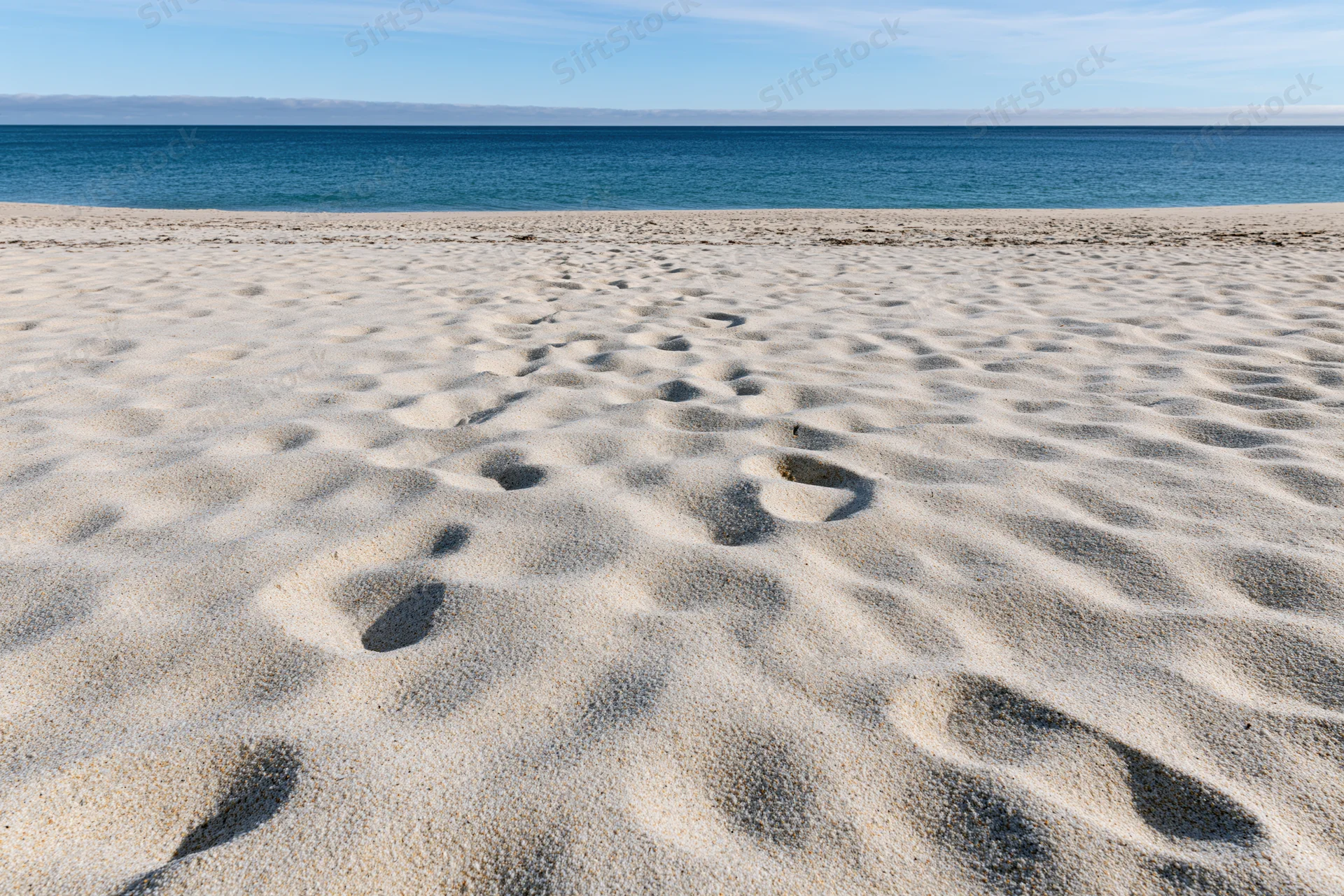 Footprints in the sand leading to the ocean at a sunny beach