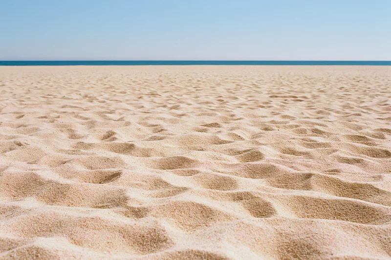 Textured sand on a beach with ocean and sky in the distance