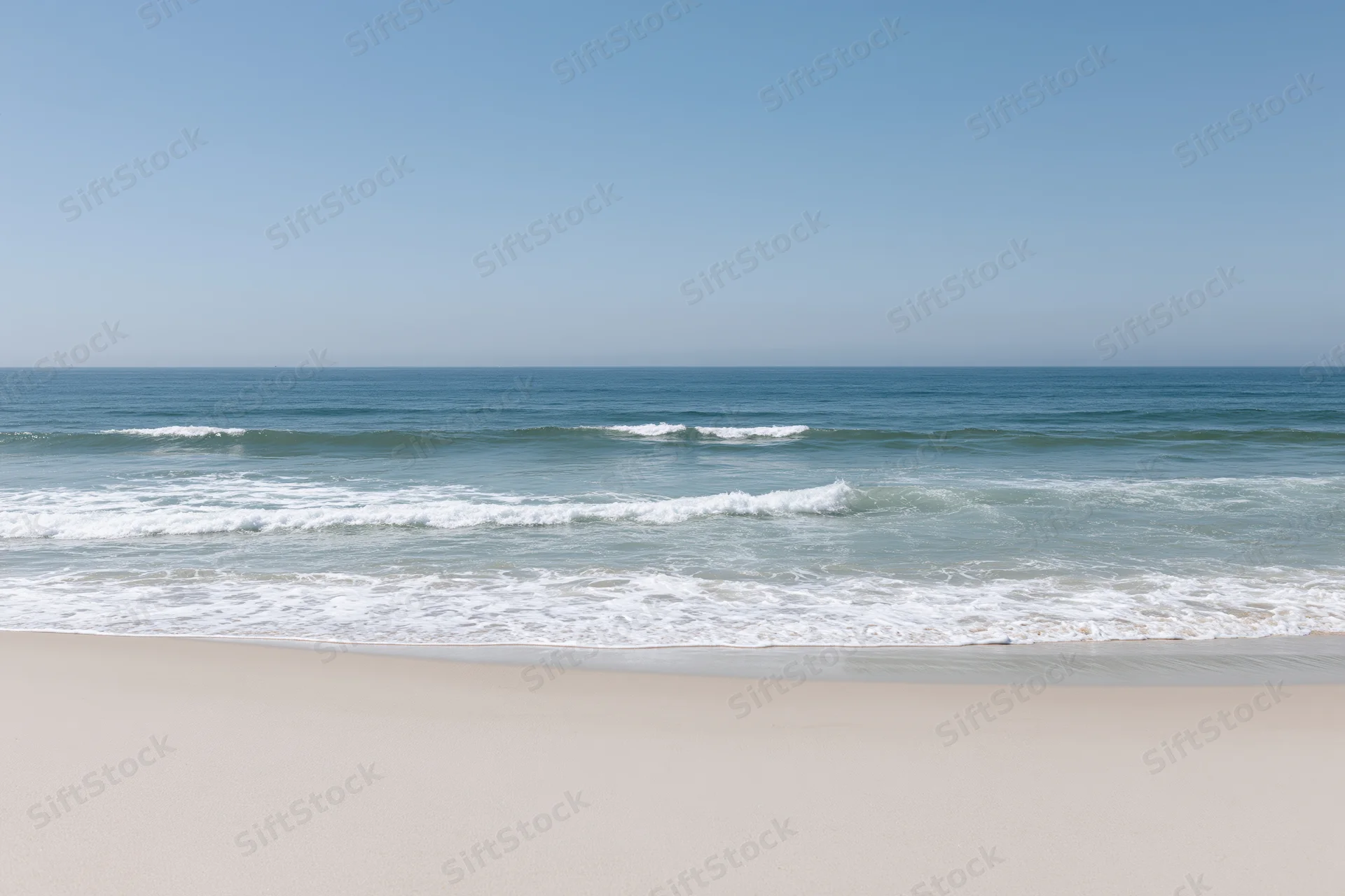 Gentle waves rolling onto a sandy beach under a clear blue sky