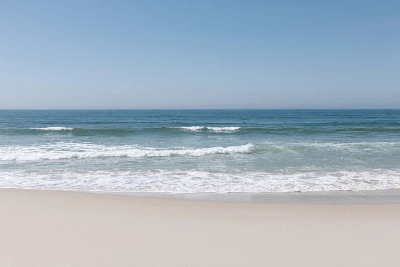 Gentle waves rolling onto a sandy beach under a clear blue sky