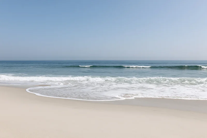 Waves breaking on a sandy beach under a clear blue sky