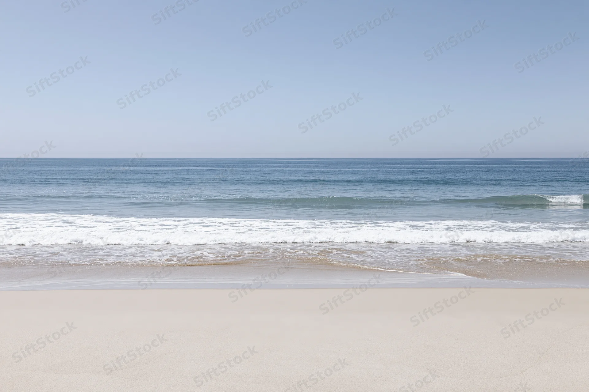 Calm ocean waves rolling onto a sandy beach under a clear blue sky