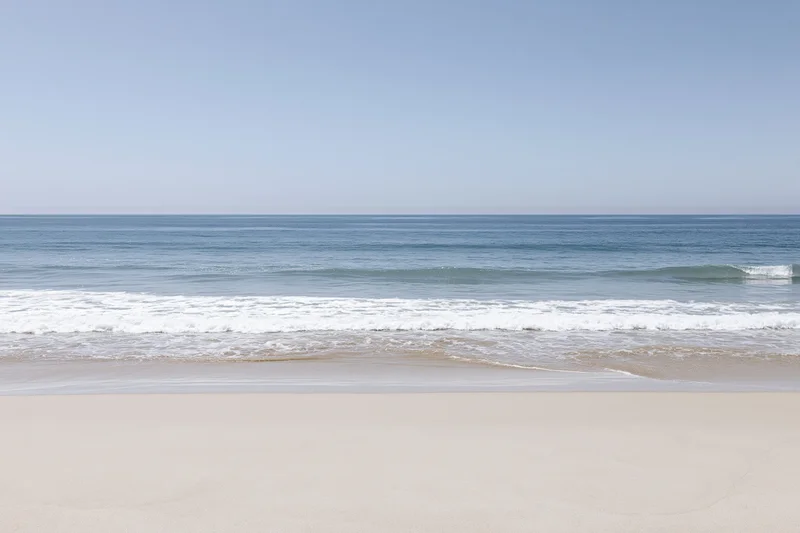 Calm ocean waves rolling onto a sandy beach under a clear blue sky