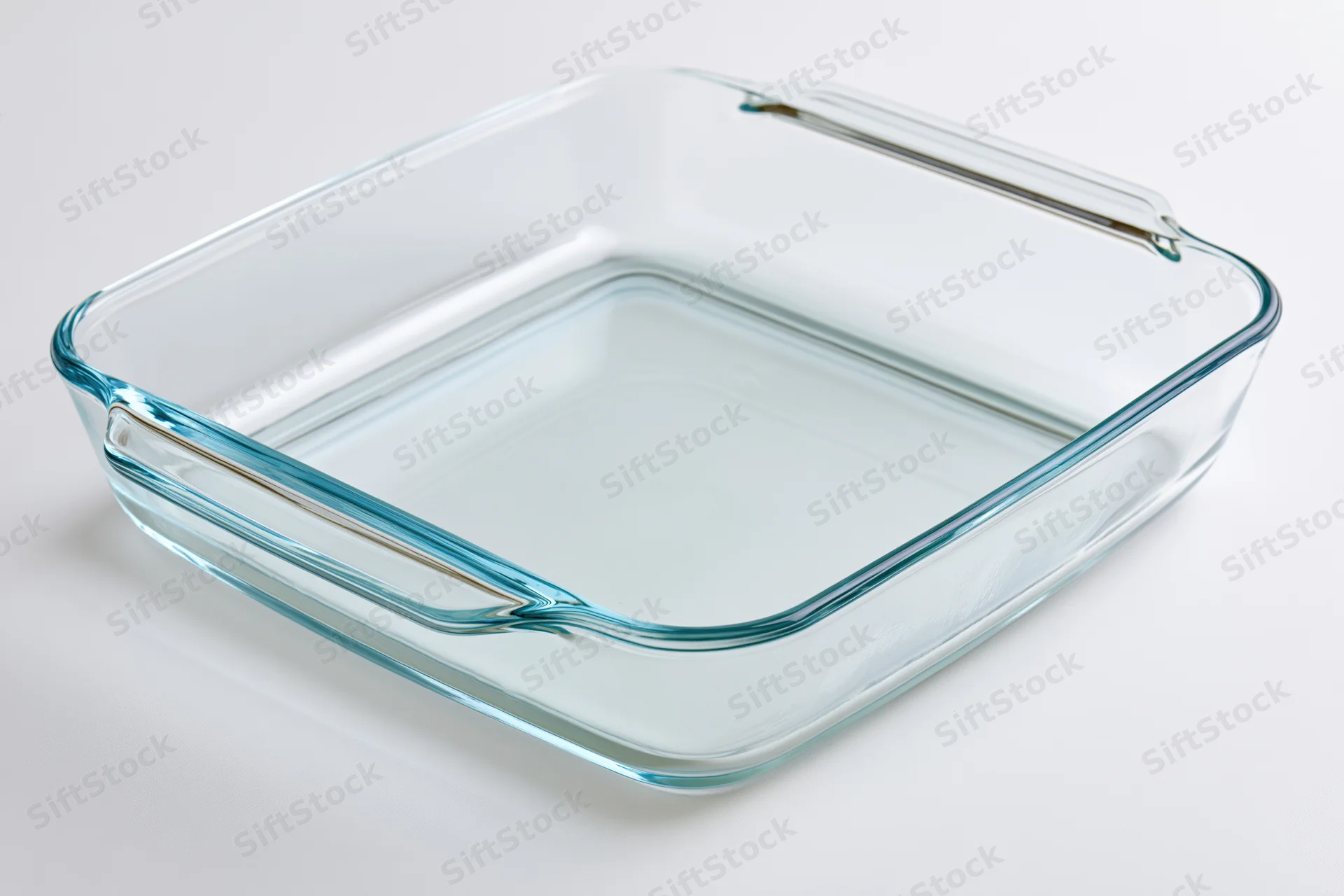 Clear glass baking dish on white surface with handles and transparent sides