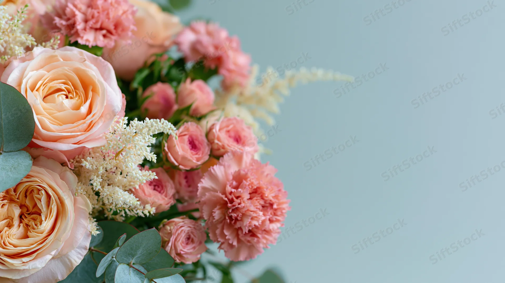 A bouquet of pink roses, peonies and eucalyptus arranged in soft pastel tones against a light blue background