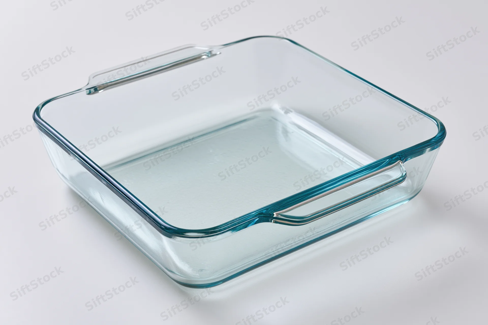 Transparent glass baking dish with handles on white background