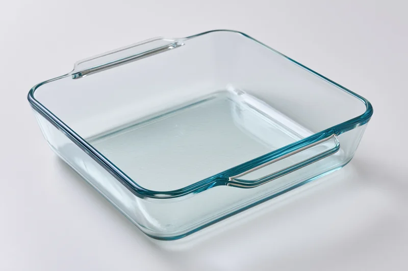 Transparent glass baking dish with handles on white background