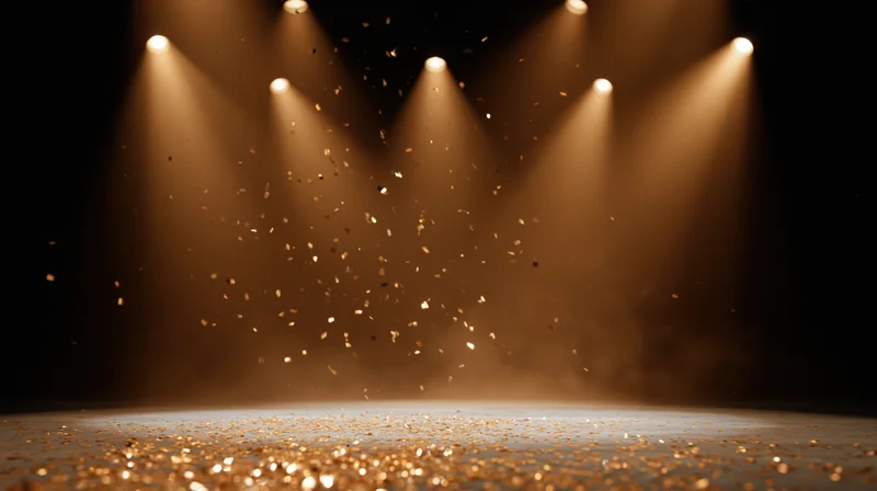 Stage lit by spotlights with falling golden confetti and glitter on the floor