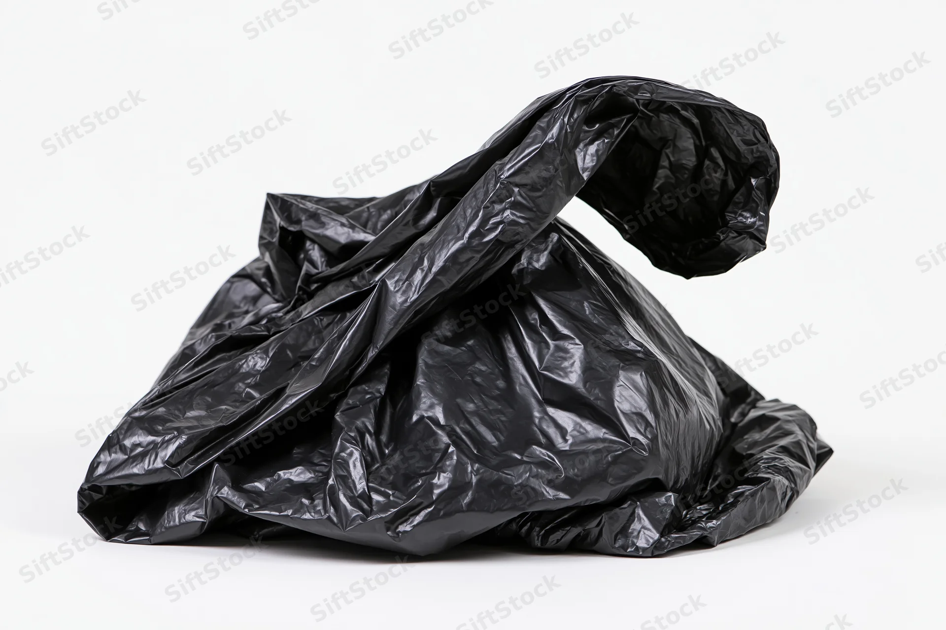 Crumpled black plastic garbage bag resting on white surface