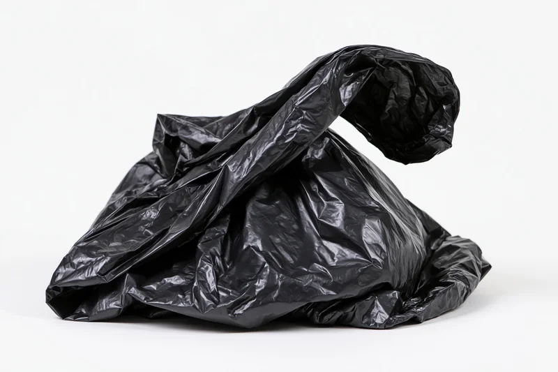 Crumpled black plastic garbage bag resting on white surface