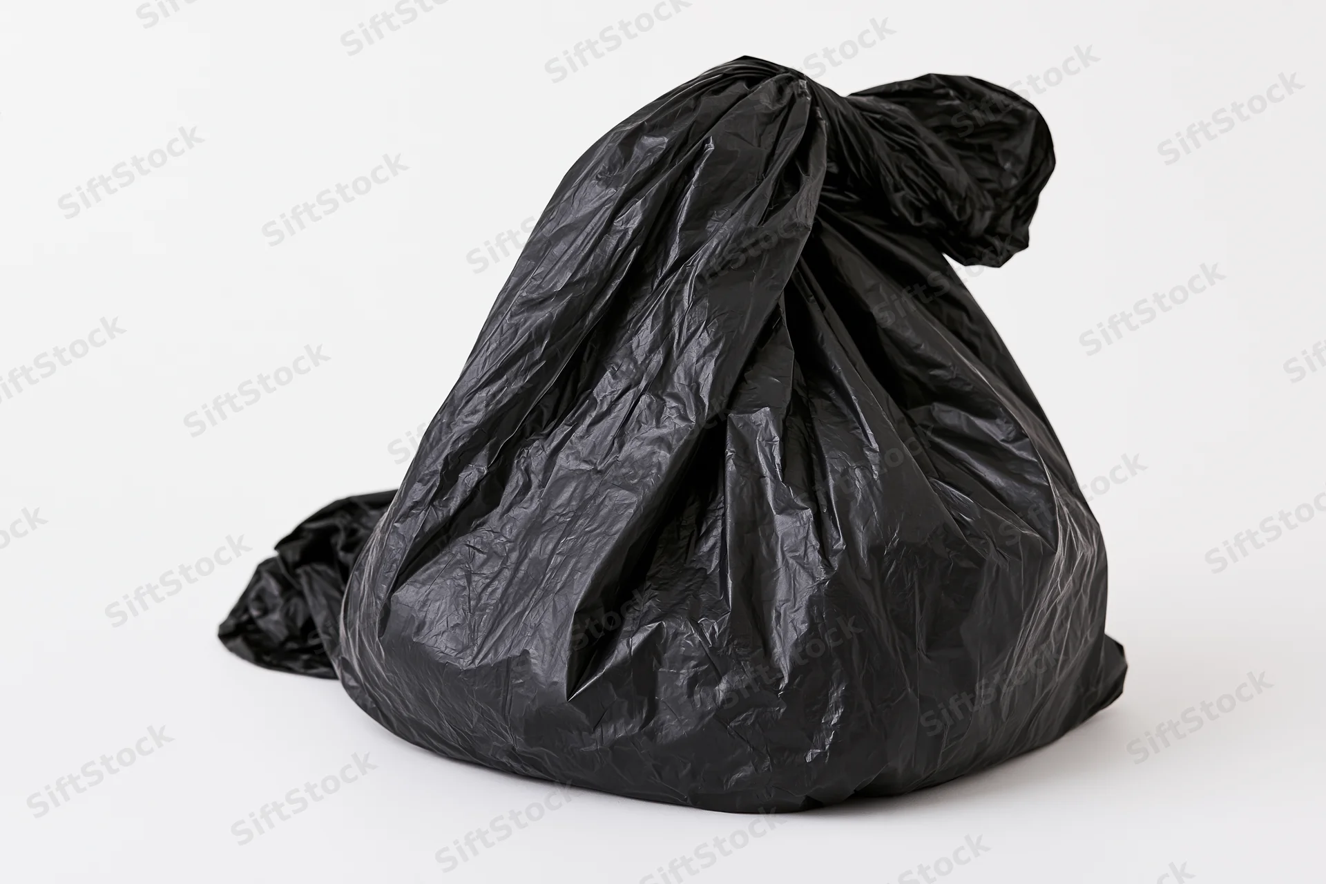 Black plastic garbage bag tied and crumpled on white background