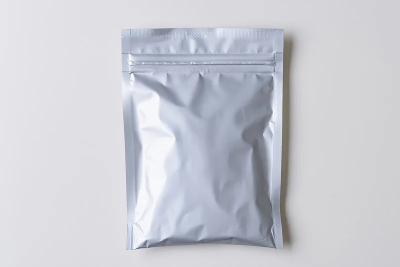 Silver mylar zip-lock pouch lying flat on white background
