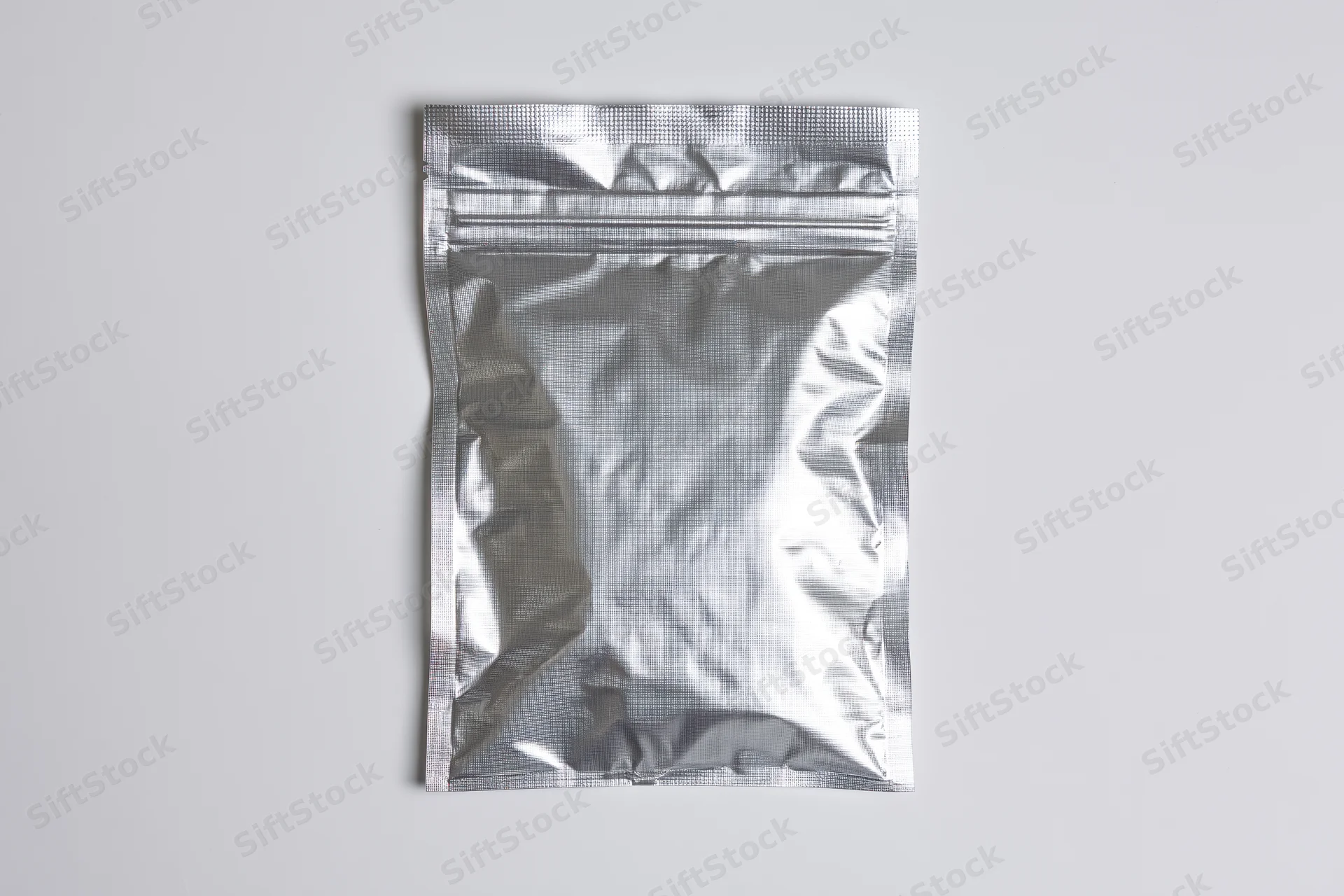 Silver mylar zip-lock pouch lying flat on white surface