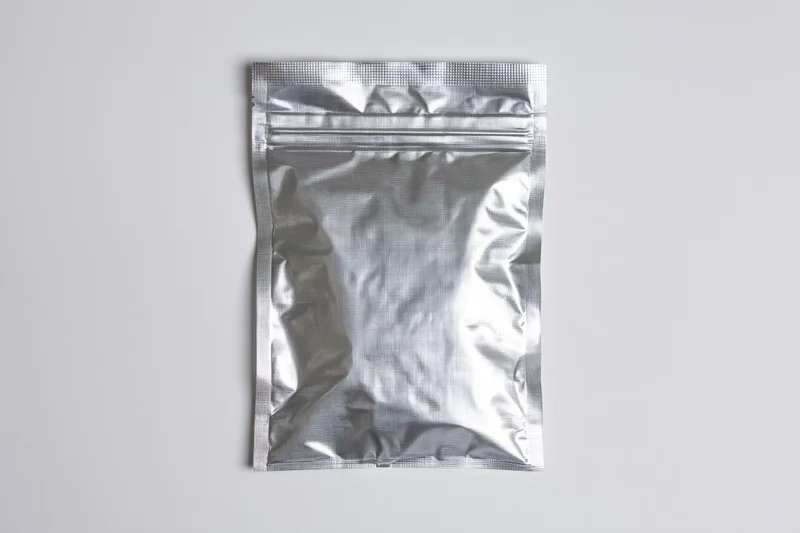 Silver mylar zip-lock pouch lying flat on white surface