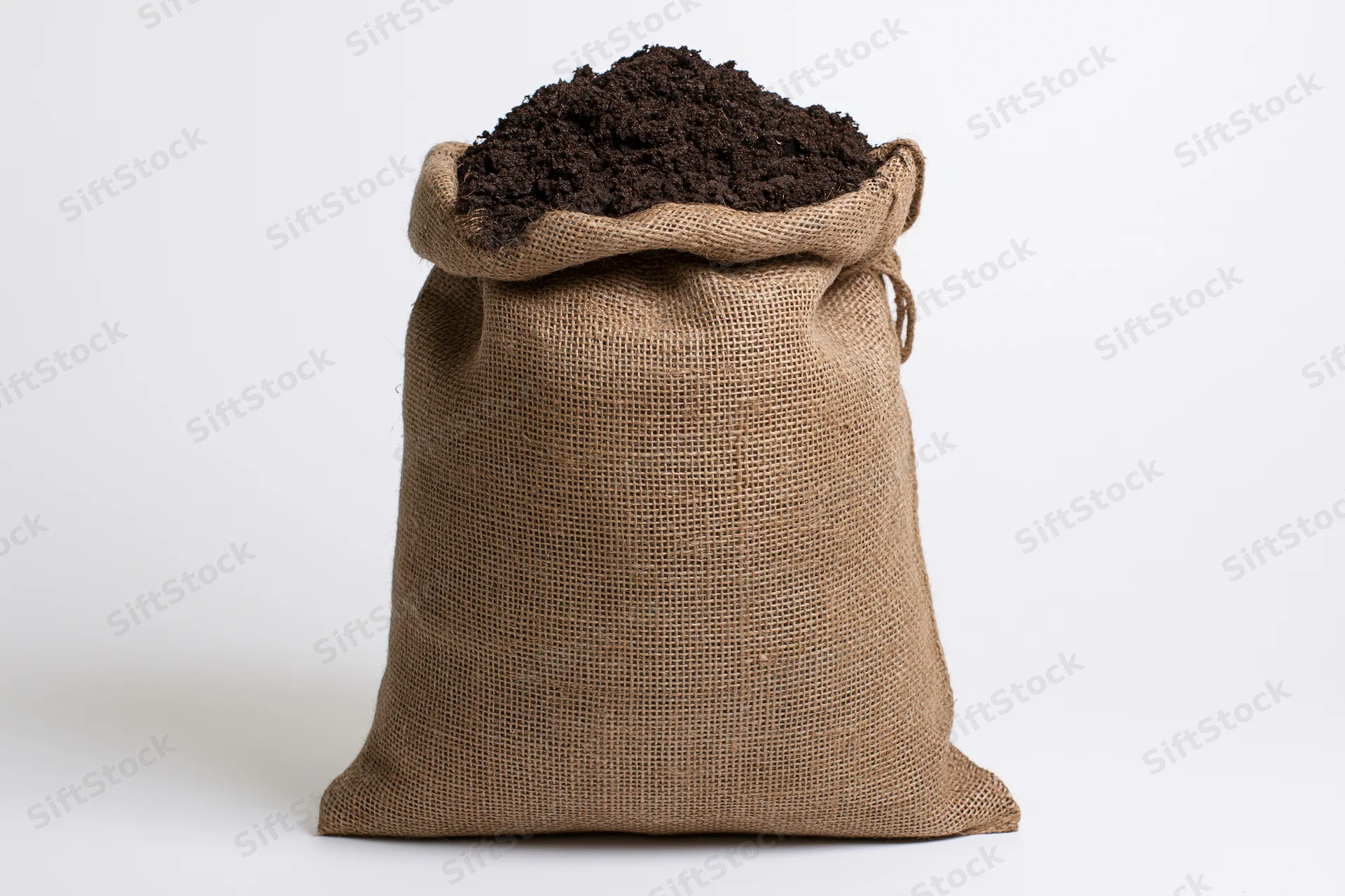 Burlap sack filled with dark brown potting soil on white background