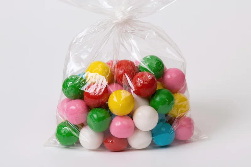 Colorful gumballs in a transparent plastic bag on white background