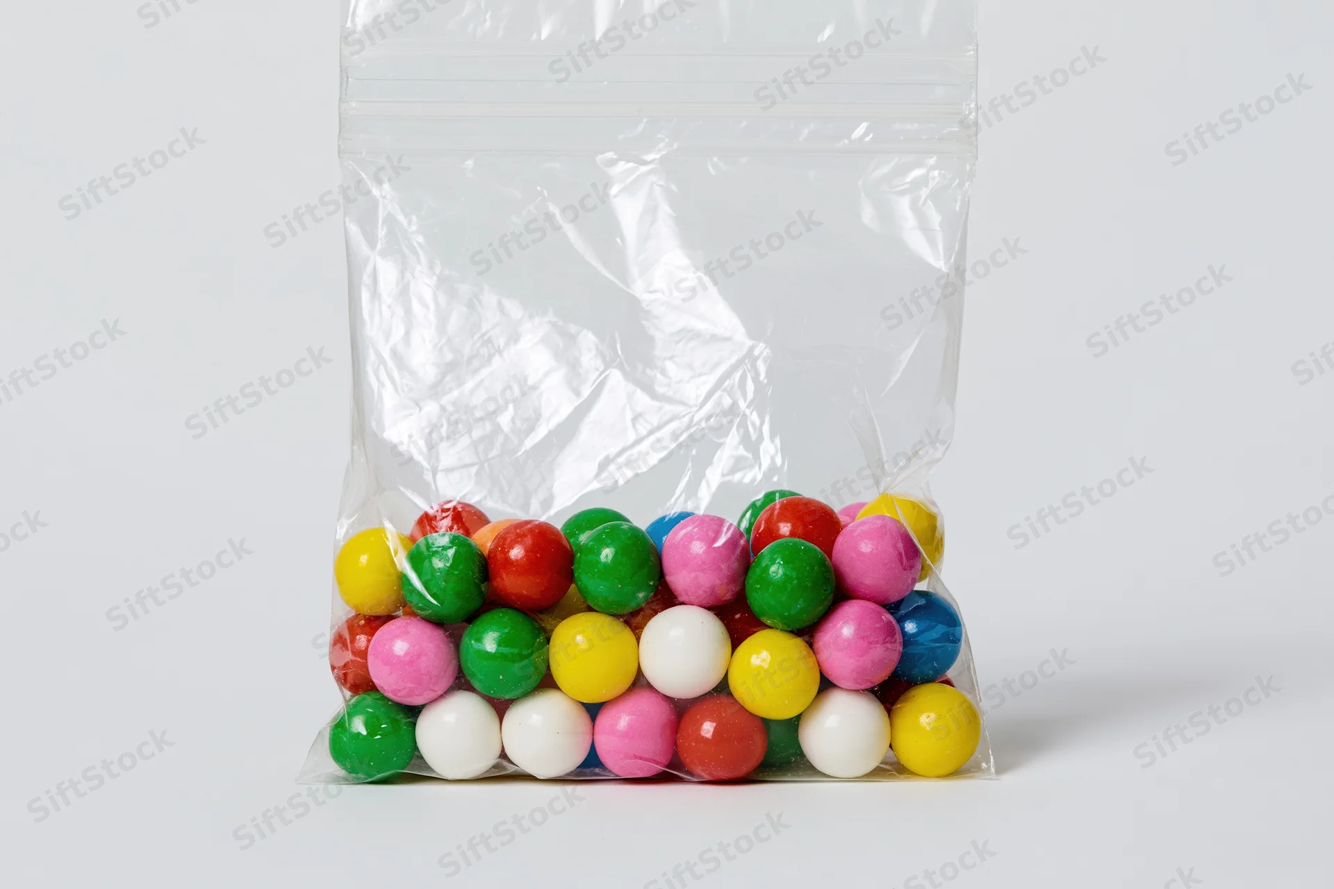 Colorful gumballs in a transparent plastic bag on white background