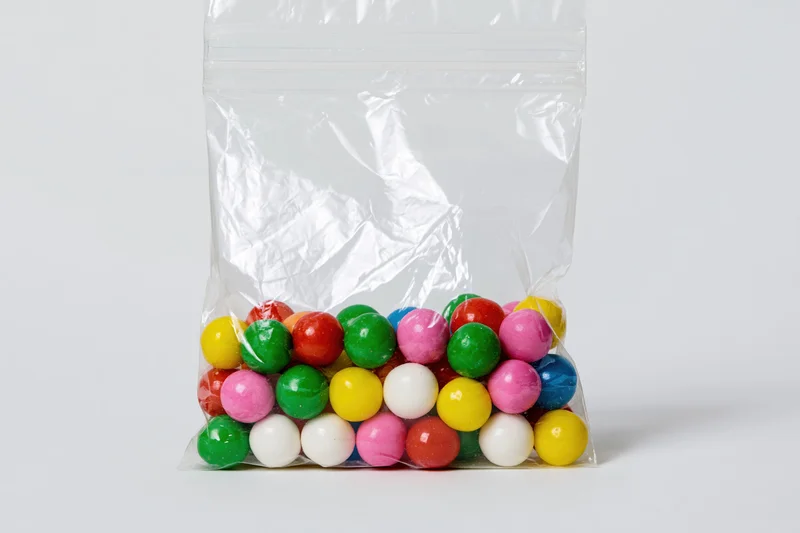 Colorful gumballs in a transparent plastic bag on white background