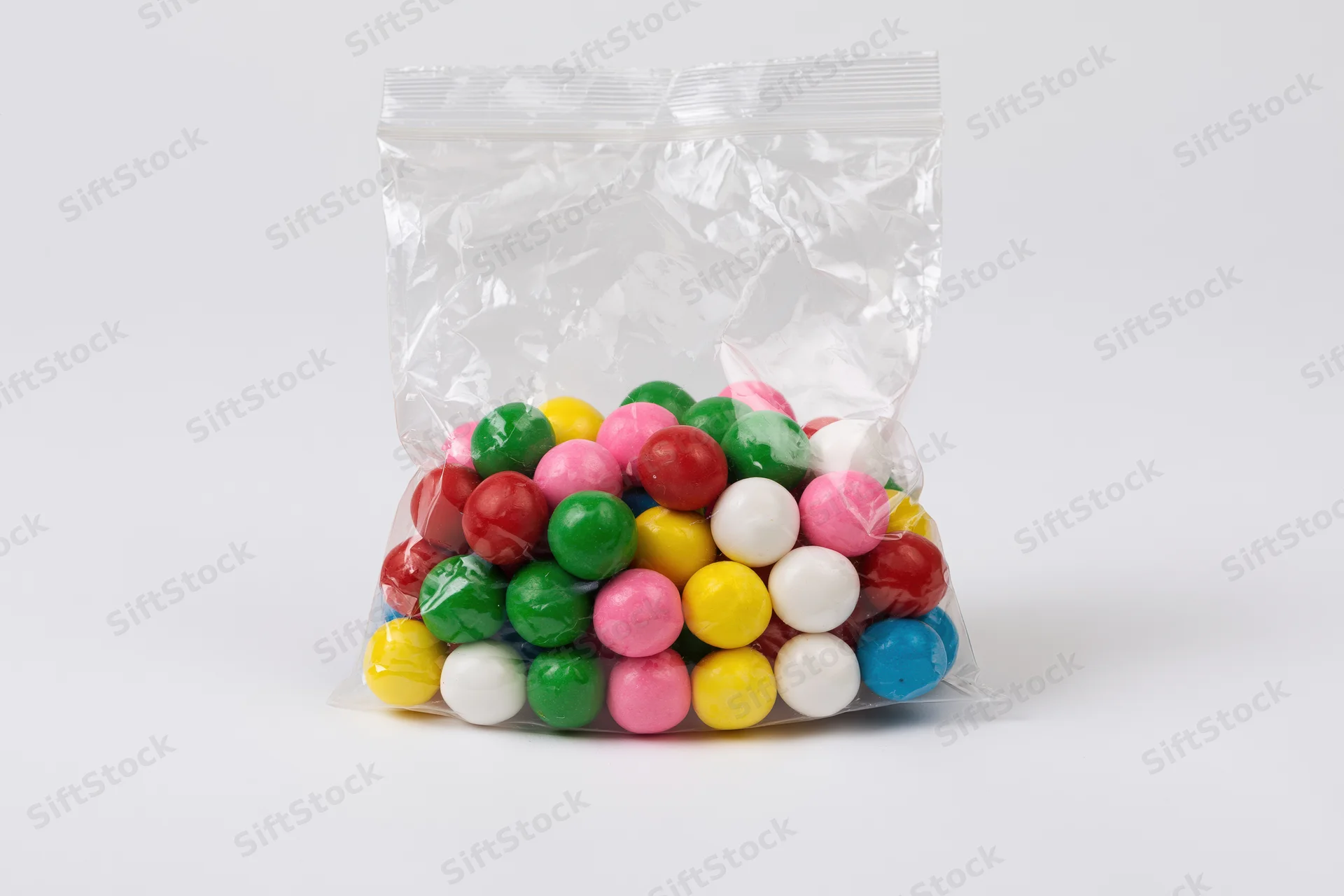 Colorful gumballs in a transparent plastic bag on white background