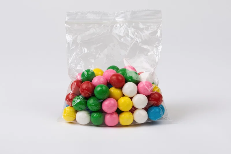 Colorful gumballs in a transparent plastic bag on white background