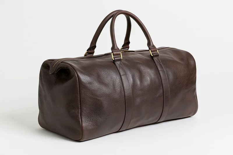 Dark brown full-grain leather duffle bag with two top handles on white background