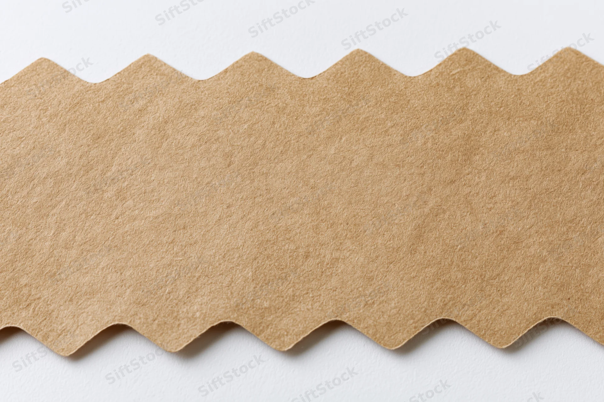 Flat kraft paper strip with zigzag cut edge on white background