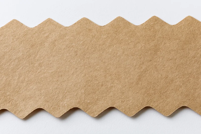 Flat kraft paper strip with zigzag cut edge on white background