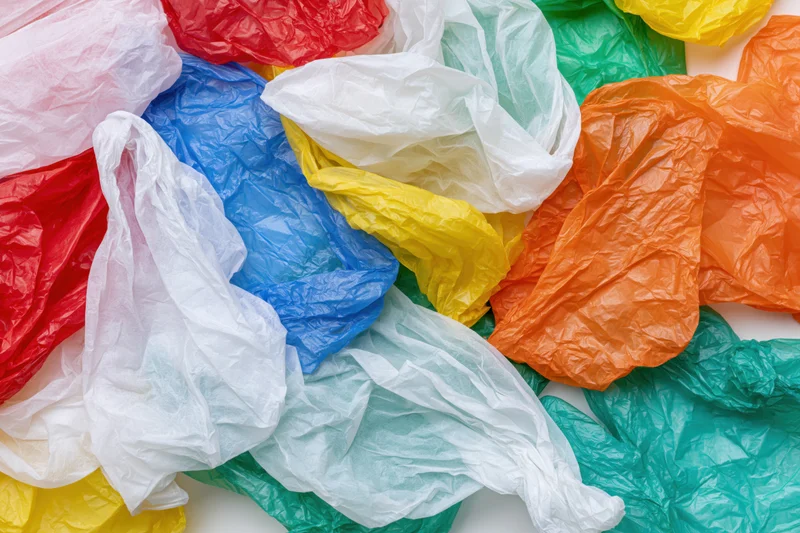Crumpled plastic shopping bags in multiple colors scattered on a white surface