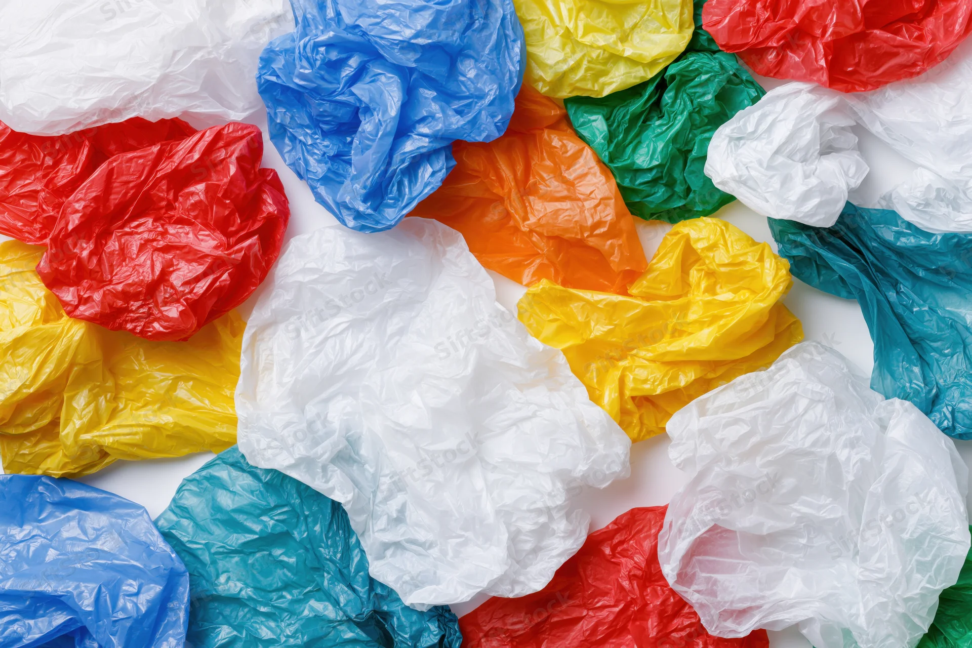 Crumpled plastic shopping bags scattered on white surface in overhead view