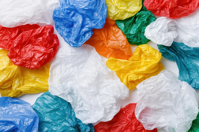 Crumpled plastic shopping bags scattered on white surface in overhead view