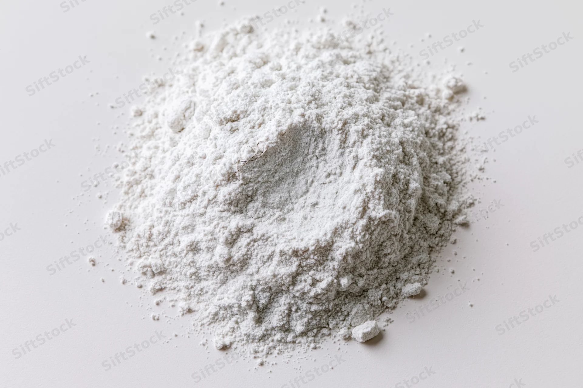 Loose pile of fine white powder scattered on a flat white surface