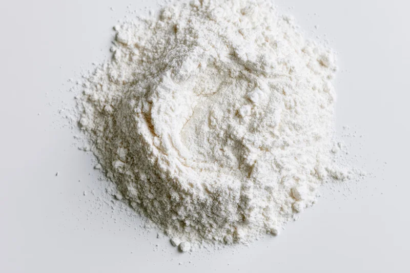 A pile of fine white powder scattered on a flat white surface