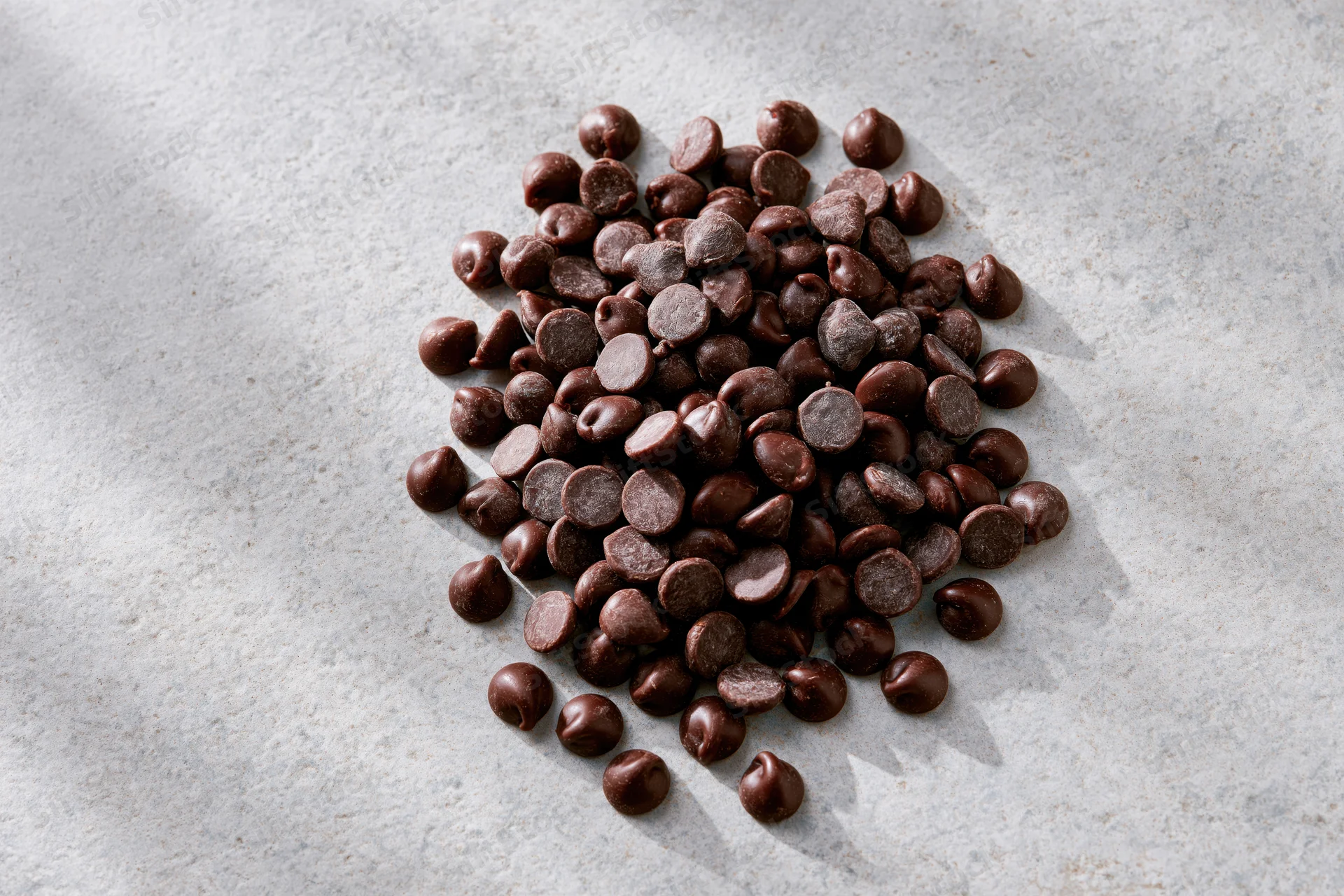 Pile of semi-sweet chocolate chips scattered on a gray marble surface