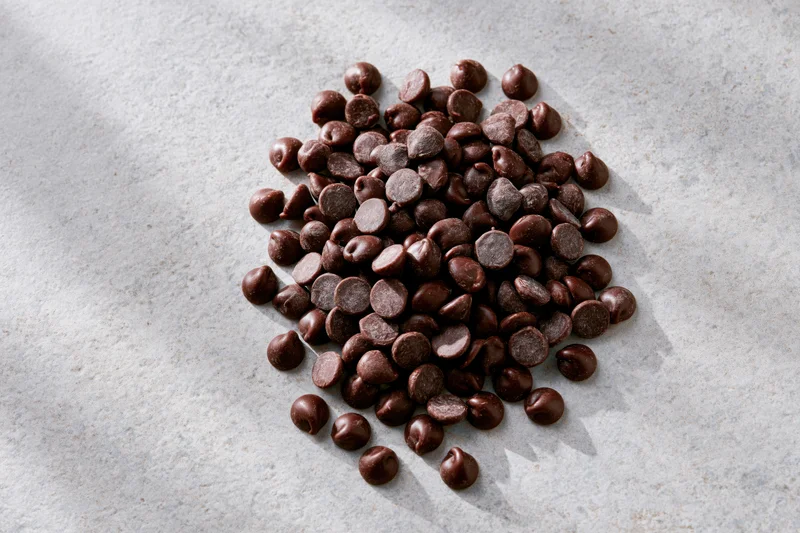 Pile of semi-sweet chocolate chips scattered on a gray marble surface