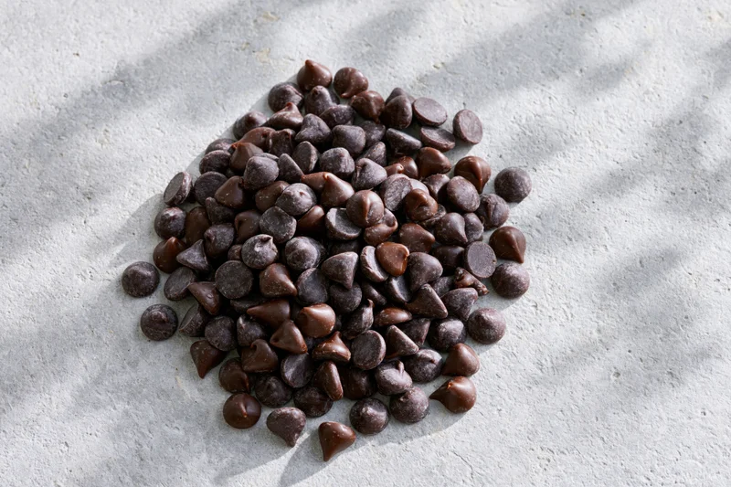 Pile of semi-sweet chocolate chips scattered on a gray stone surface