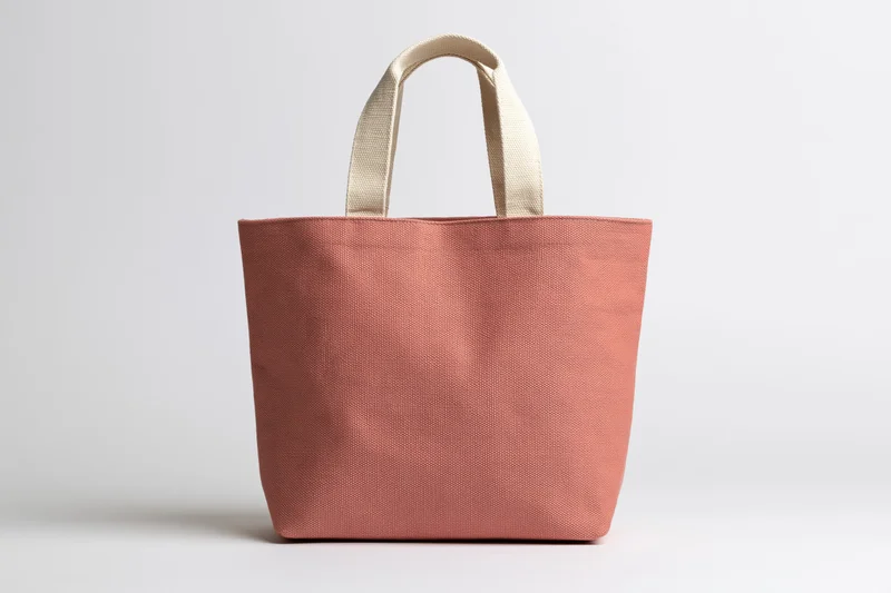 Peach canvas tote bag standing upright on white background