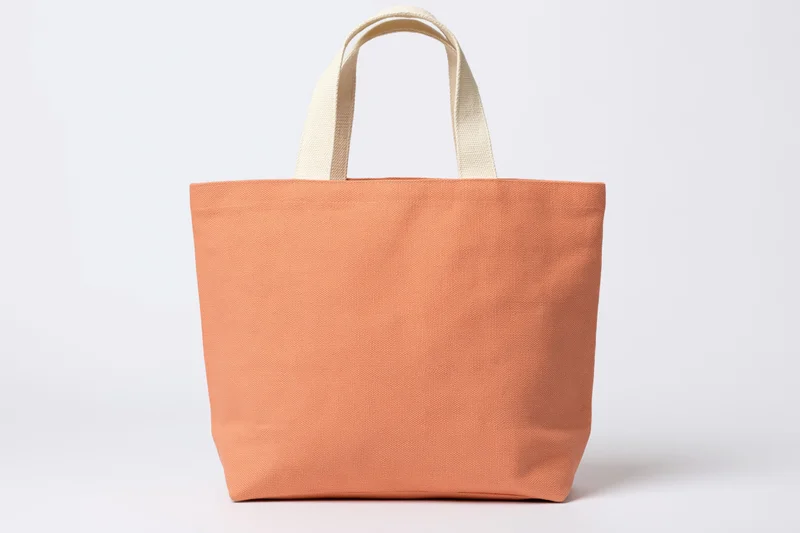 Peach canvas tote bag standing upright on white background