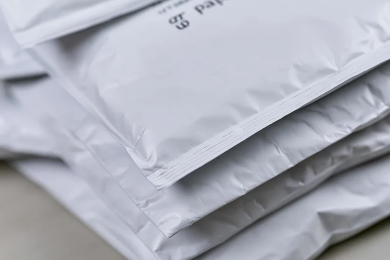 Stack of white poly mailer shipping bags on a flat surface