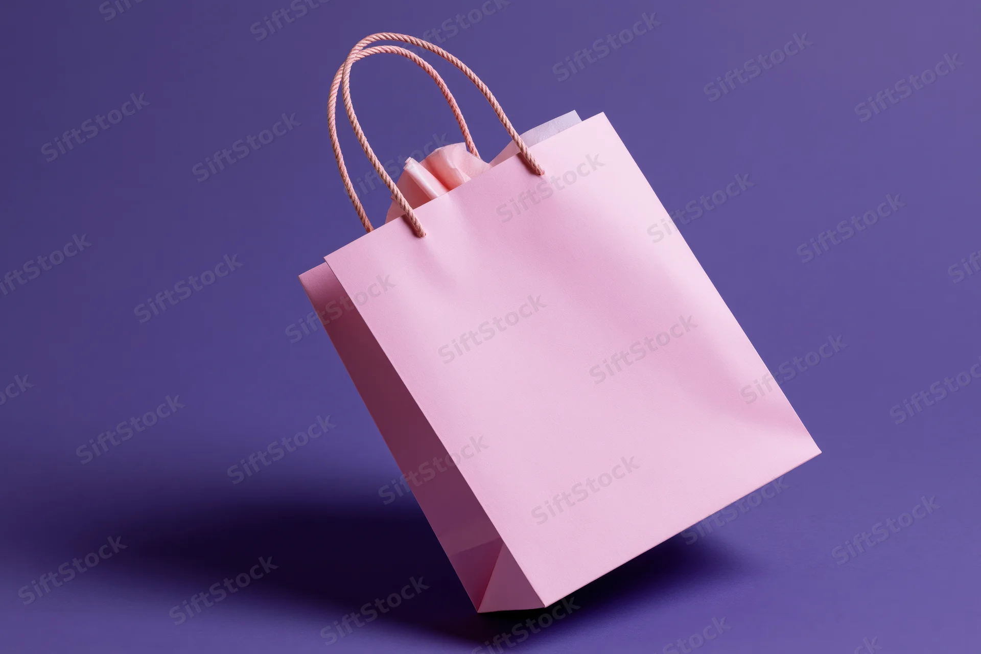 Pink paper shopping bag tilted and balanced on one corner against purple background