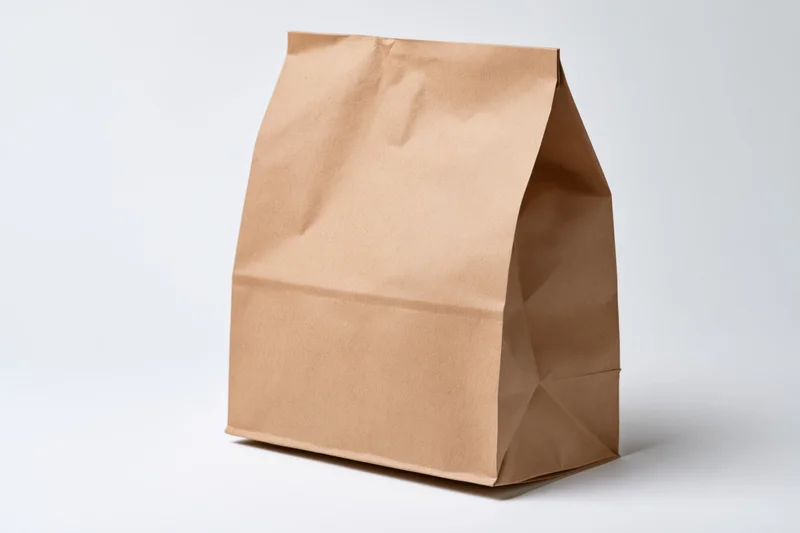 Brown kraft paper bag standing upright on white surface