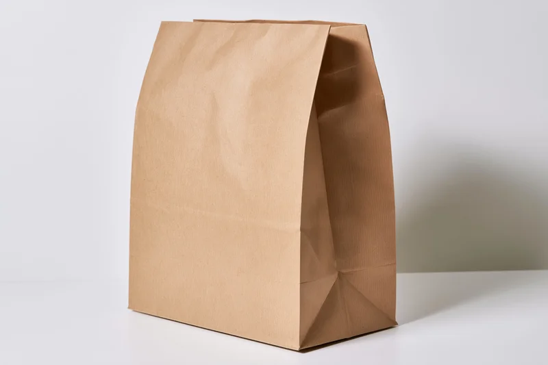 Brown kraft paper bag standing upright on a white surface