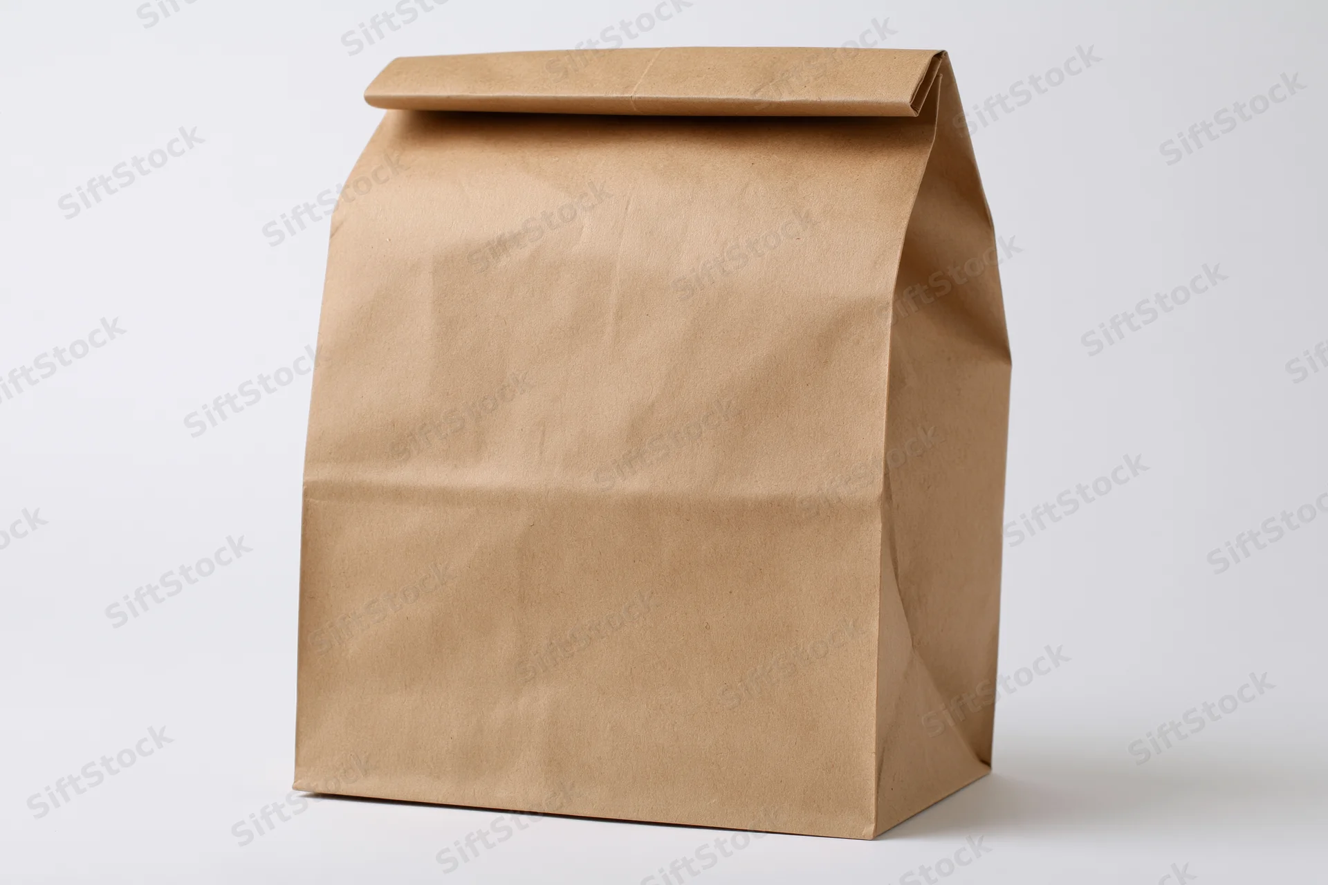 Brown kraft paper lunch bag standing upright with folded top on white background