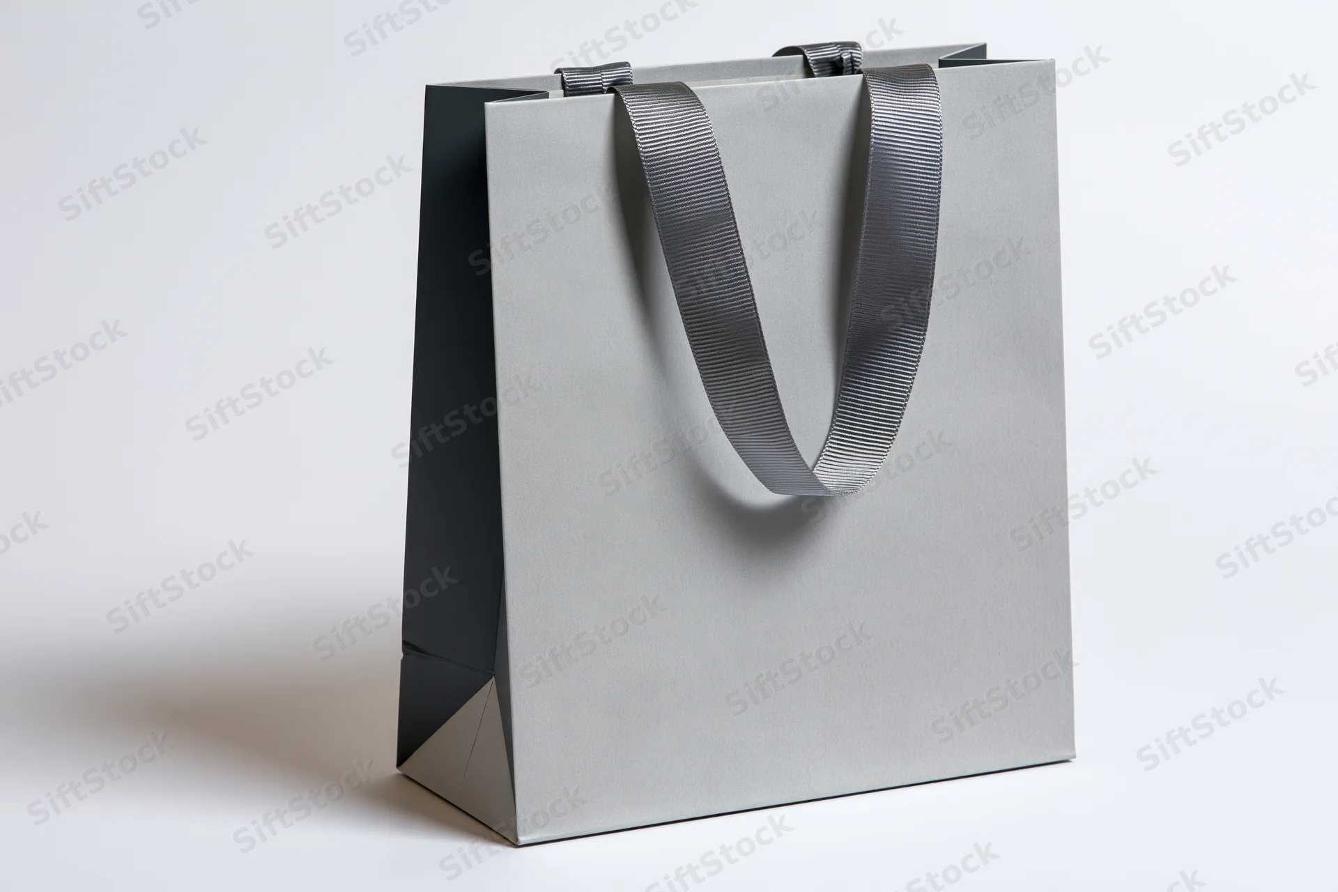 Plain grey paper shopping bag with woven fabric ribbon handles on white background